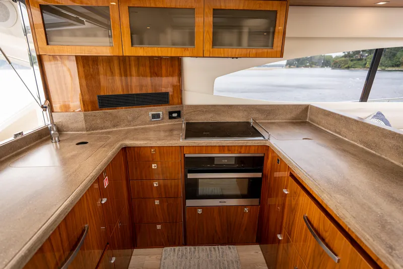 Slide: The Image of Luxurious kitchen interior of 2017 Riviera 6000 Sport Yacht with wood cabinetry and modern appliances. - 12