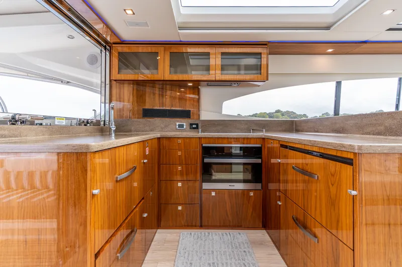 Slide: The Image of Luxurious 2017 Riviera 6000 Sport Yacht kitchen with sleek wood cabinetry and modern appliances. - 15