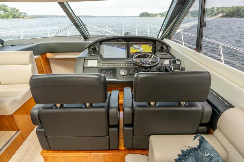 Slide: The Image of Interior of 2017 Riviera 6000 Sport Yacht with dual black leather seats and navigation controls. - 26