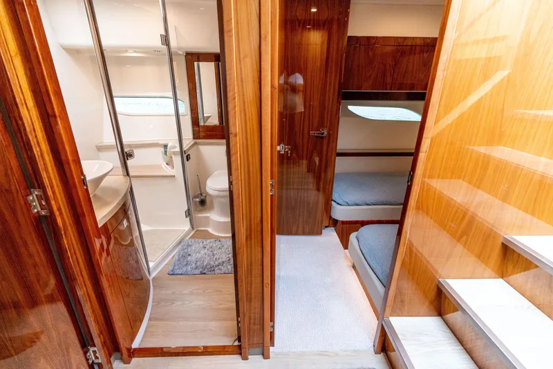 Slide: The Image of 2017 Riviera 6000 Sport Yacht interior with wooden finishes, bathroom, and cozy sleeping area. - 33