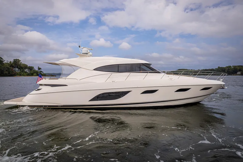 Slide: The Image of 2017 Riviera 6000 Sport Yacht cruising on a calm waterway under a partly cloudy sky. - 4