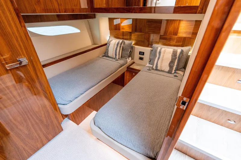 Slide: The Image of 2017 Riviera 6000 Sport Yacht cabin with twin beds, wooden paneling, and modern decor. - 49