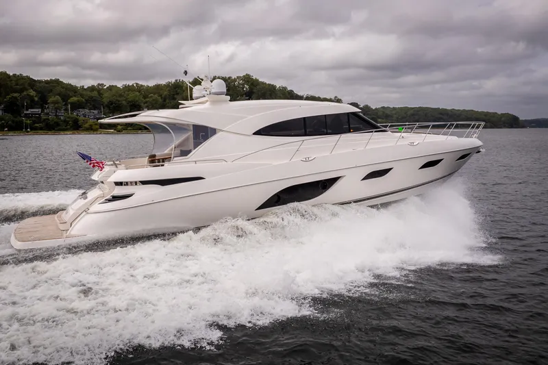 Slide: The Image of 2017 Riviera 6000 Sport Yacht cruising on a lake under cloudy skies. - 6