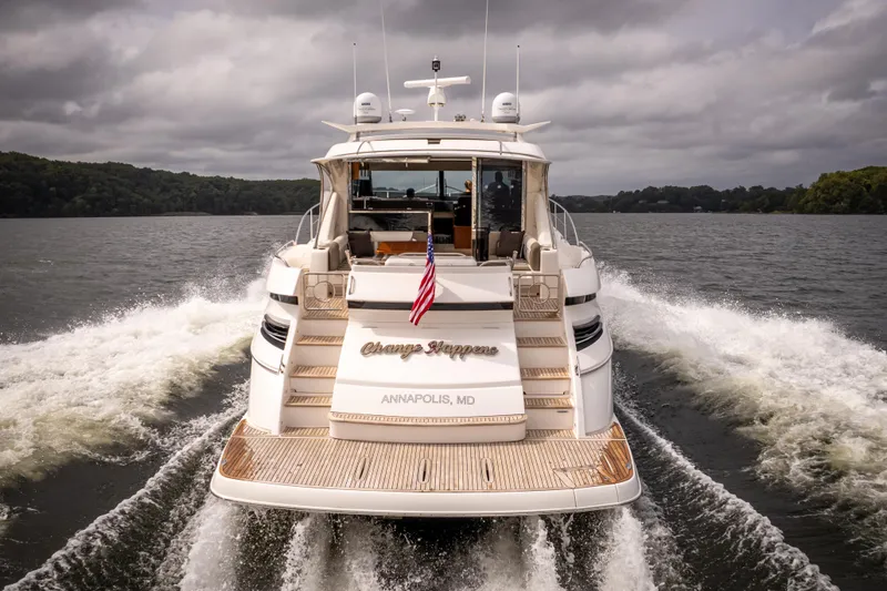 Slide: The Image of 2017 Riviera 6000 Sport Yacht cruising on a lake, rear view with American flag. - 9