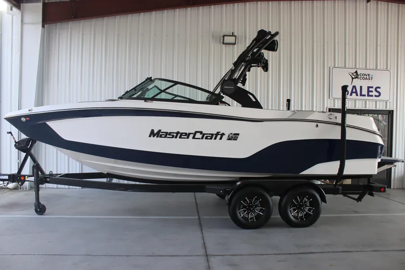 The Image of 2025 MasterCraft XT22 boat on trailer in showroom, side view. - 0