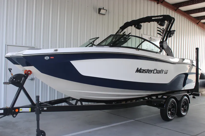 Slide: The Image of 2025 MasterCraft XT22 boat on trailer, displayed in a showroom setting. - 1