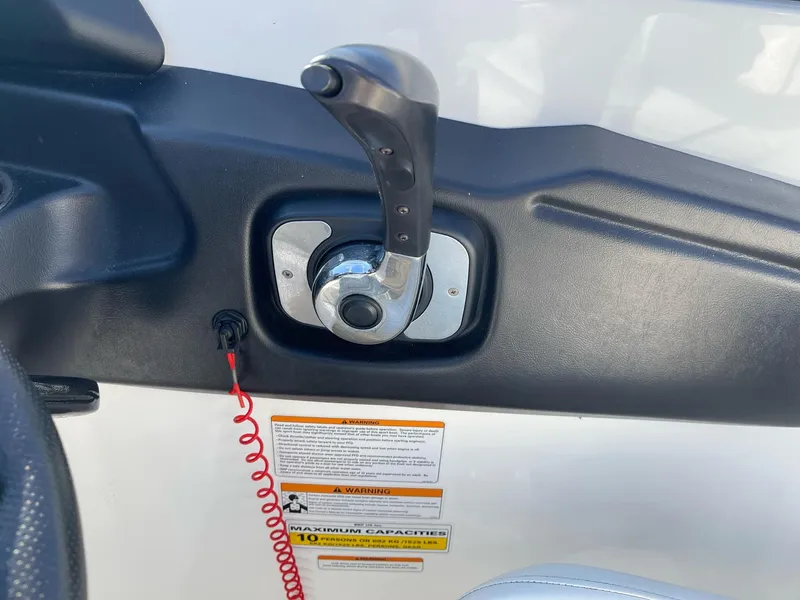 Slide: The Image of 2010 Sea-Doo 210 Challenger throttle control with safety lanyard and warning labels. - 12