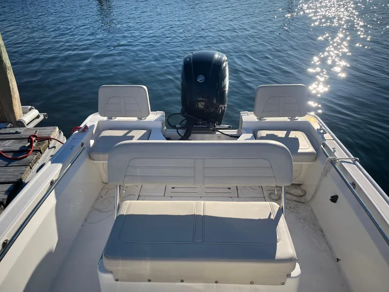 Slide: The Image of 2020 Boston Whaler 170 Montauk boat interior with seating and motor, docked on sunny water. - 11