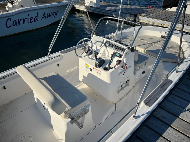 Slide: The Image of 2020 Boston Whaler 170 Montauk boat docked, featuring a clean, spacious interior and steering console. - 5