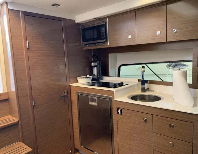 Slide: The Image of 2018 Cruisers 390 Express Coupe kitchen with wood cabinetry and modern appliances. - 12