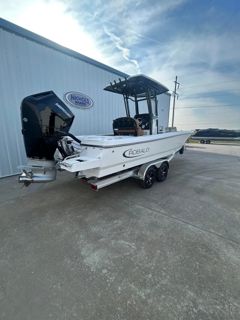 Slide: The Image of 2025 Robalo 246 Cayman boat on trailer, parked outside a building. - 2