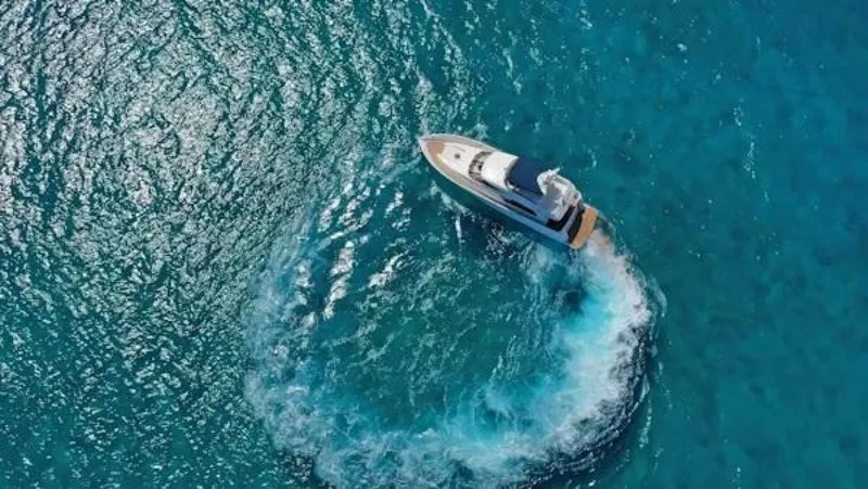Slide: The Image of Aerial view of 2004 McKinna Pilothouse yacht making a circular wake in clear blue water. - 4