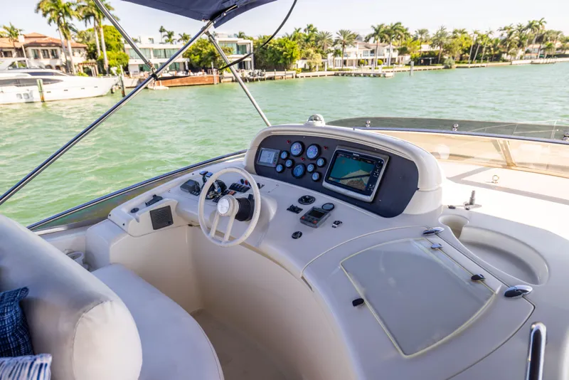 Slide: The Image of Cockpit of 2005 Azimut 68 yacht with navigation controls, overlooking serene waterfront homes. - 10