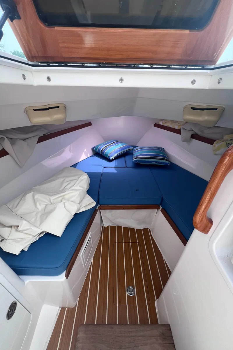 Slide: The Image of 2011 Hunt Yachts Harrier 25 cabin with blue cushions and wooden flooring. - 4