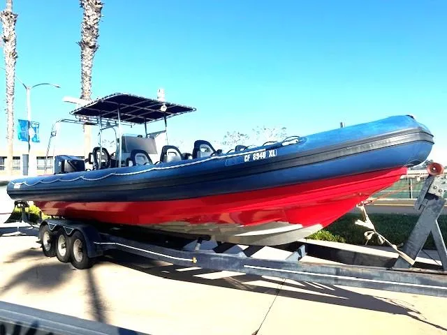 Slide: The Image of 2022 Allmand 31 RIB boat on trailer, blue and red design, sunny day. - 0