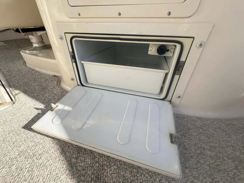 Slide: The Image of Open storage compartment on 2002 Chaparral Sunesta 243 boat, featuring a white interior bin. - 33