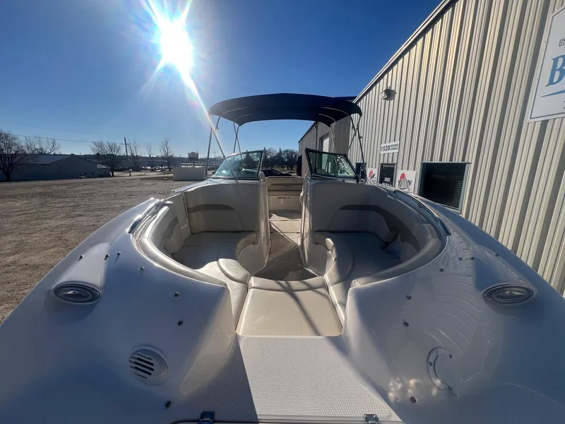 Slide: The Image of 2002 Chaparral Sunesta 243 boat with open seating, parked outdoors under bright sun. - 5