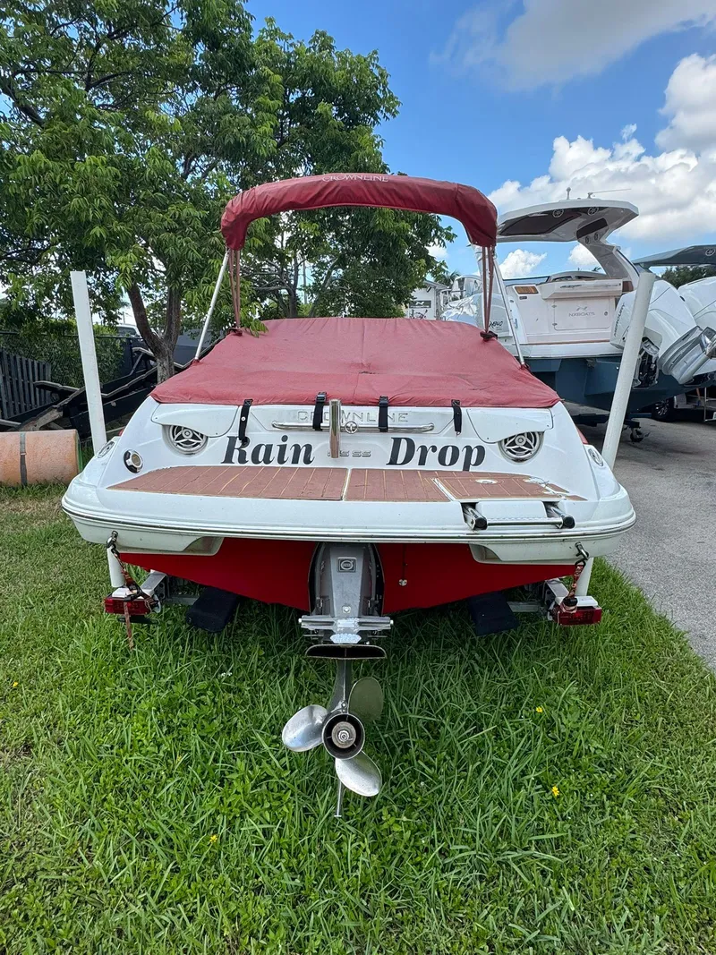 Slide: The Image of 2010 Crownline 195SS boat named "Rain Drop" with red cover, parked on grass. - 12