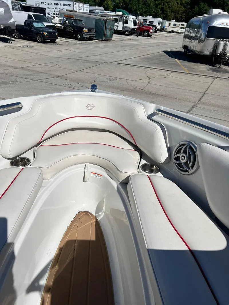 Slide: The Image of 2010 Crownline 195SS boat interior with white seating and red accents, parked in a lot. - 22