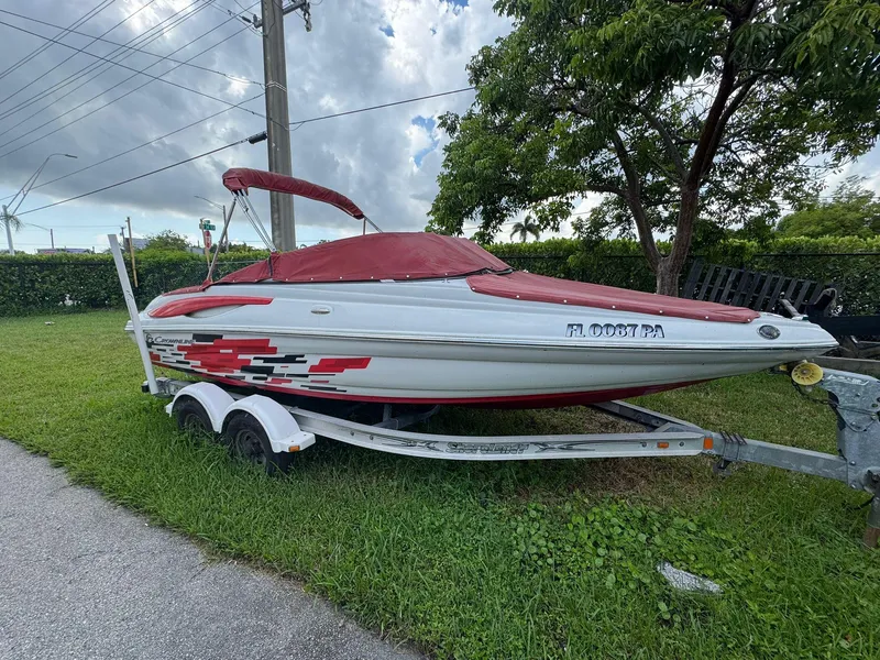 Slide: The Image of 2010 Crownline 195SS boat with red cover on trailer, parked on grass. - 4
