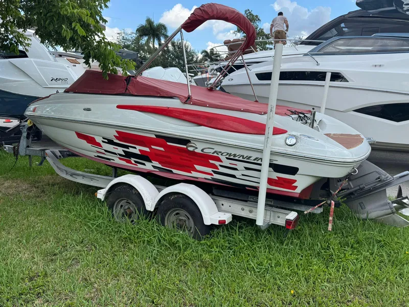Slide: The Image of 2010 Crownline 195SS boat with red and white design on a trailer, parked on grass. - 5