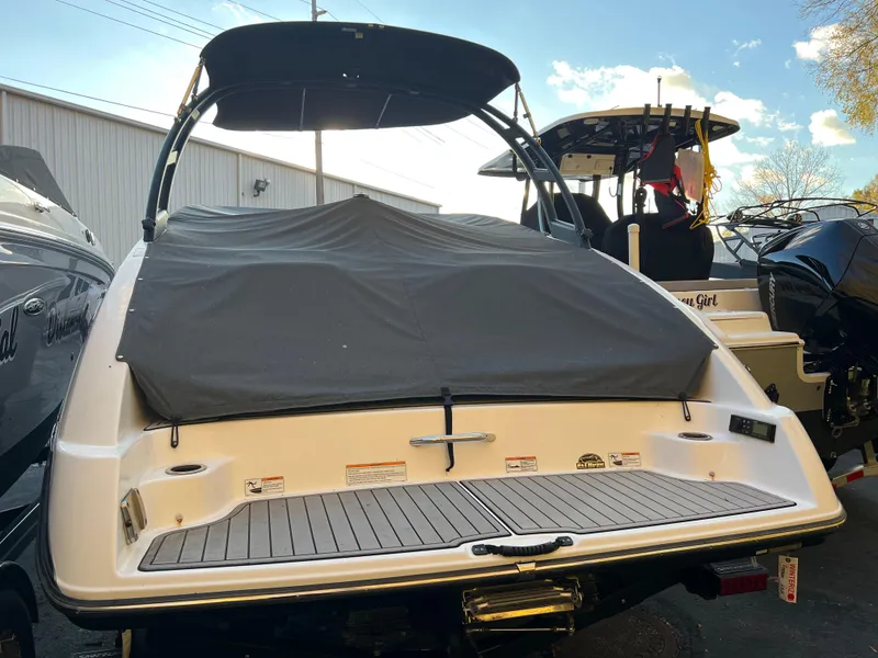 Slide: The Image of 2020 Yamaha AR240 boat with cover, rear view in marina setting. - 2