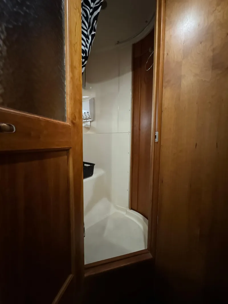 Slide: The Image of Wooden door opening to a compact shower area on a 2001 Silverton 410 Sport Bridge yacht. - 23