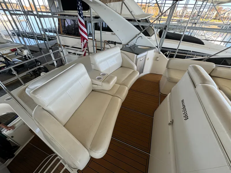 Slide: The Image of 2001 Silverton 410 Sport Bridge with white seating and wooden deck, docked in a marina. - 32
