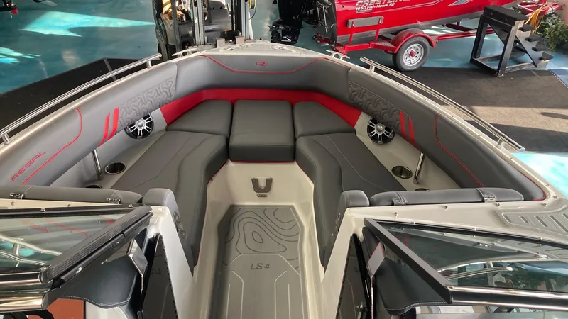 Slide: The Image of 2025 Regal LS4 boat interior with gray and red seating, speakers, and cup holders. - 10