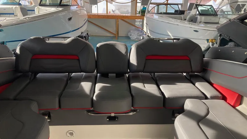 Slide: The Image of 2025 Regal LS4 boat interior with gray and red seating in a showroom. - 5