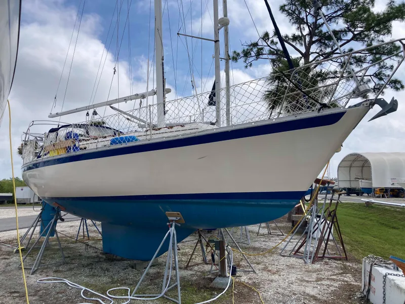 Slide: The Image of 1984 Irwin 34 Sloop sailboat on dry dock, white hull with blue trim. - 1