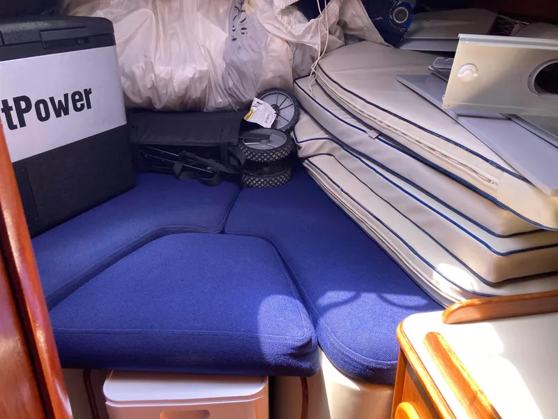 Slide: The Image of Interior of 1984 Irwin 34 Sloop with blue cushions and stacked equipment. - 6