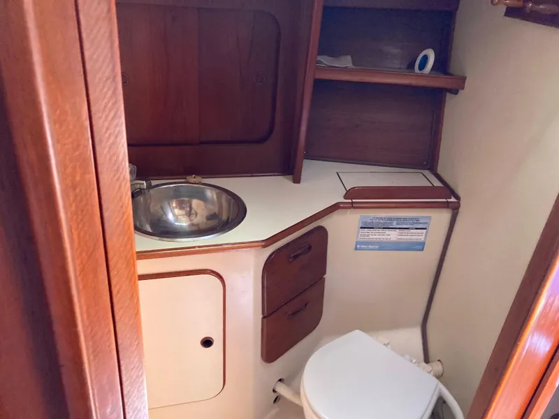 Slide: The Image of 1984 Irwin 34 Sloop bathroom with sink, toilet, and wooden cabinetry. - 7
