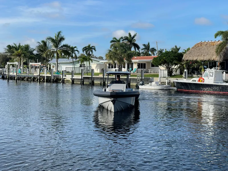 Slide: The Image of 2023 Skipper-BSK 38NC boat on a calm waterfront with palm trees. - 11