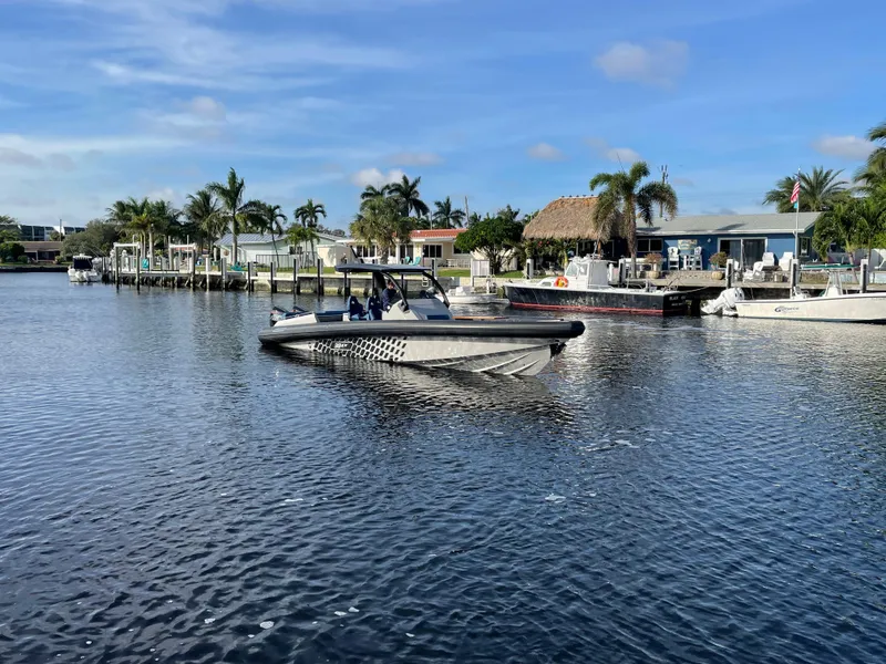 Slide: The Image of 2023 Skipper-BSK 38NC boat on a calm waterfront with palm trees. - 13