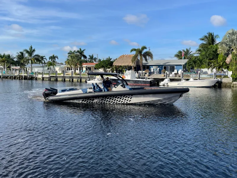 Slide: The Image of 2023 Skipper-BSK 38NC boat cruising on a sunny waterfront with palm trees. - 14