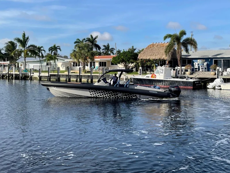 Slide: The Image of 2023 Skipper-BSK 38NC boat cruising on a sunny waterfront with palm trees. - 7