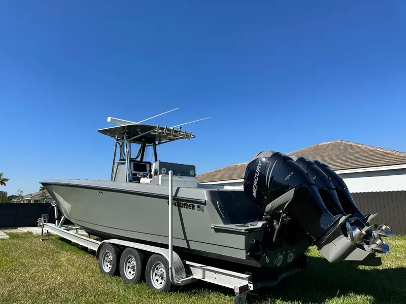 Slide: The Image of 2005 Contender 36 Open boat on trailer with Mercury engines, parked on grass. - 2