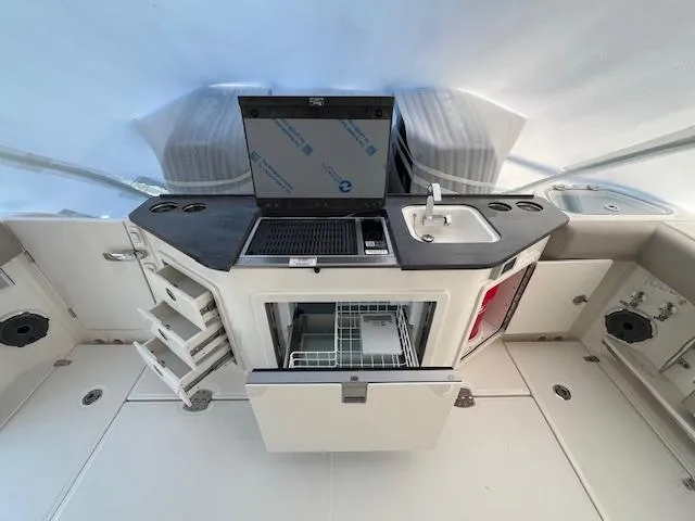 Slide: The Image of 2025 Boston Whaler 365 Conquest boat interior with kitchenette and storage. - 10