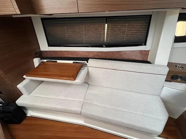 Slide: The Image of 2025 Boston Whaler 365 Conquest interior with beige seating and wooden table. - 12