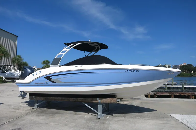 Slide: The Image of 2024 Chaparral 23 SSi OB boat on display, blue and white design, sunny day. - 0