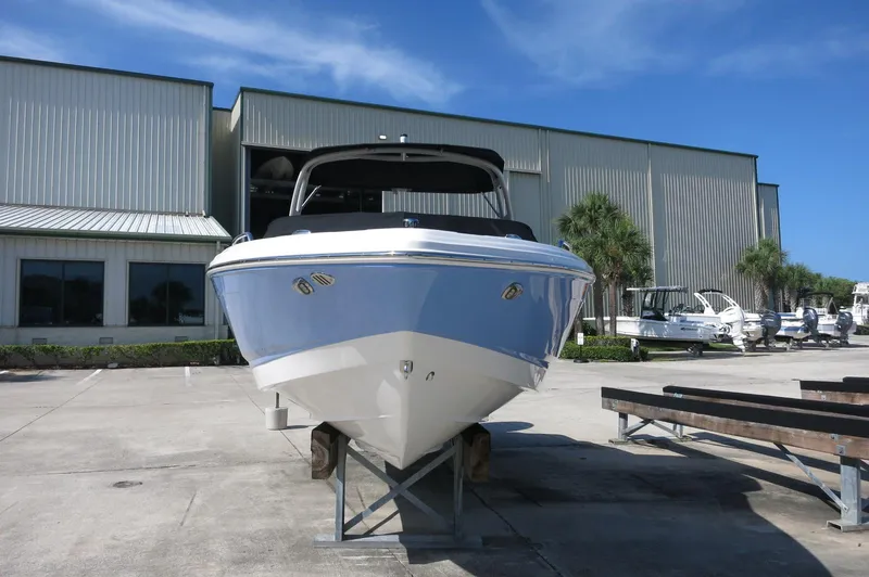 Slide: The Image of 2024 Chaparral 23 SSi OB boat displayed outdoors near a warehouse. - 2