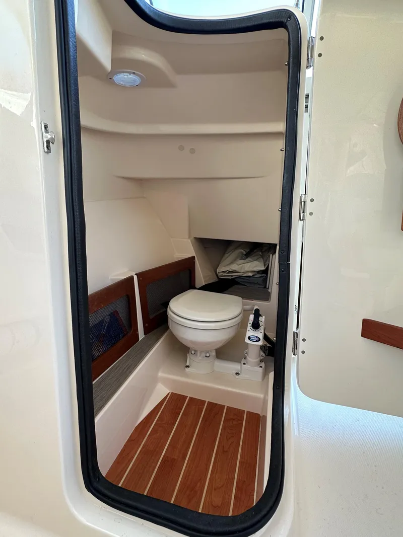 Slide: The Image of 2021 Grady-White Freedom 235 boat interior with toilet and wooden flooring. - 15