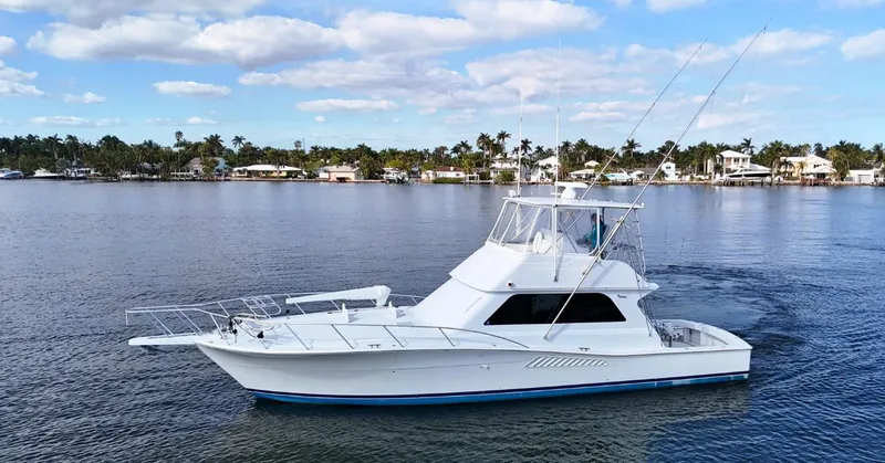 The Image of 1999 Viking 47 Convertible yacht cruising on a calm lake under a blue sky. - 0