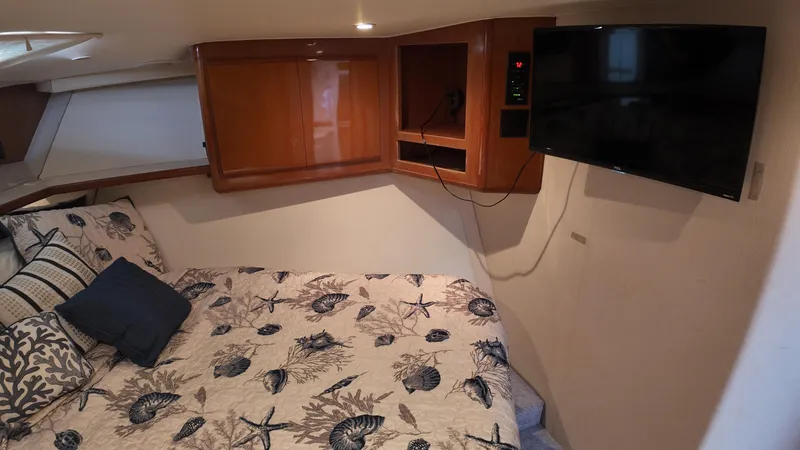 Slide: The Image of Cozy bedroom in 1999 Viking 47 Convertible yacht with TV and nautical-themed bedding. - 23