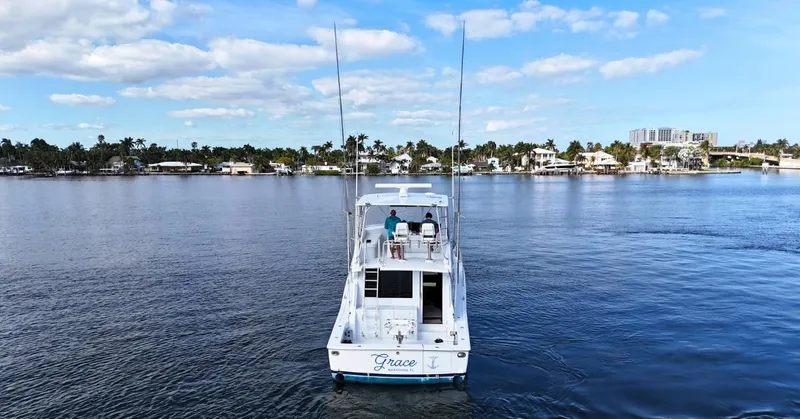 Slide: The Image of 1999 Viking 47 Convertible yacht on calm water, clear sky, coastal background. - 3