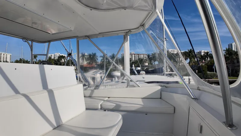 Slide: The Image of 1999 Viking 47 Convertible yacht interior with white seating and clear windows, under blue sky. - 35