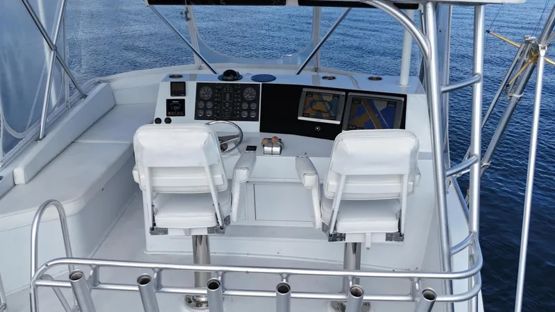 Slide: The Image of 1999 Viking 47 Convertible yacht helm with dual white captain chairs and navigation equipment. - 4