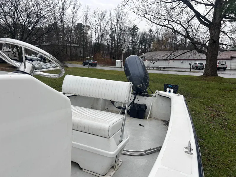 Slide: The Image of 2020 Flying Point Boatworks FP 21 with white seating and outboard motor, parked on grass. - 10