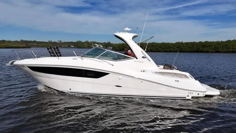 Slide: The Image of 2015 Sea Ray 330 Sundancer cruising on a calm lake under a clear blue sky. - 0